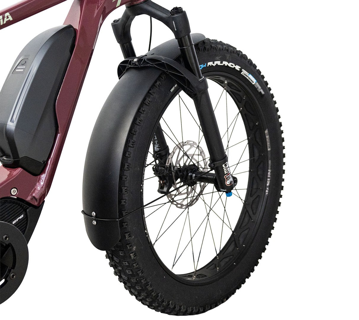 Lähikuva Helkama-sähköpyörän etupyörästä, jossa on paksu rengas, jousitettu haarukka ja HELKAMA: FATBIKE LOKASUOJASETTI ETEEN JA TAAKSE musta suojalevy. Myös pyörän runko ja akku ovat osittain näkyvissä.