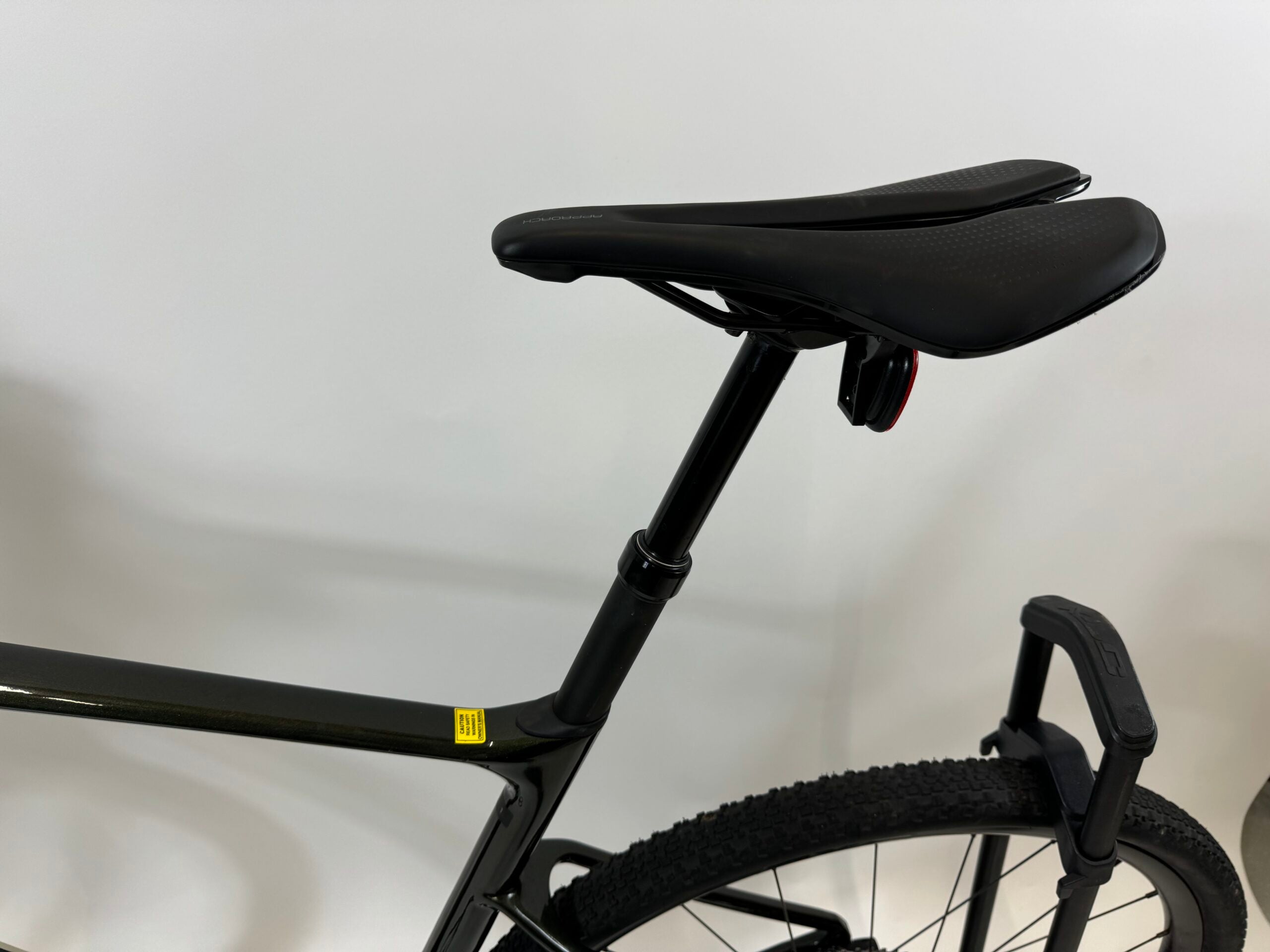 SÄHKÖPYÖRÄT.NETin lähikuva Giant Revolt Advanced 1 Käytetty gravelpyörä *NOPEIMMALLE* näyttää sen mustan satulan, istuintolpan, nupukkarenkaan ja U-lukon hiilikuiturunko-kehyksessä valkoista taustaa vasten.