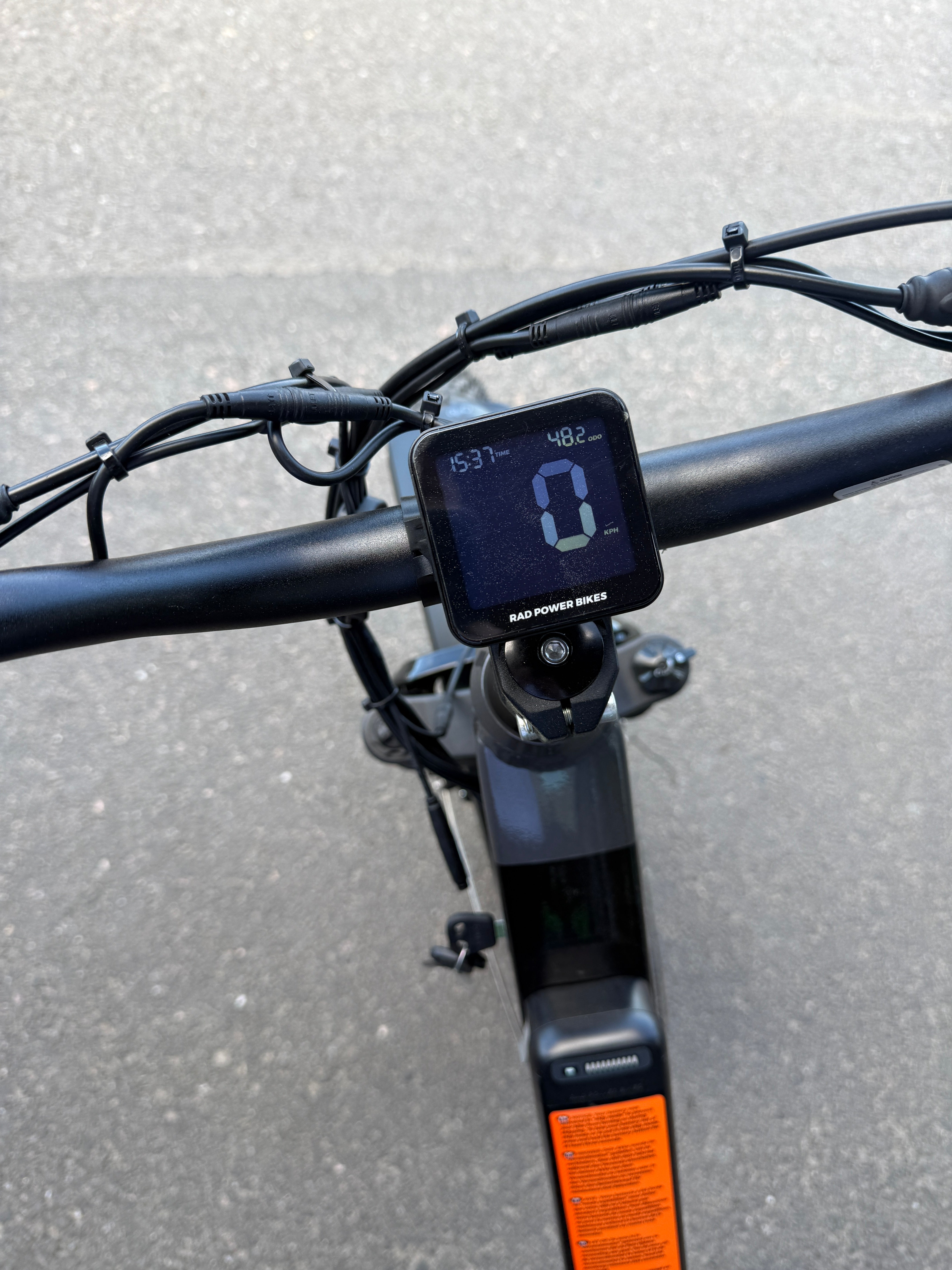 Lähikuva SÄHKÖPYÖRÄT.NET Rad Power Bikes Radrhino 6 Plus Step Thru käytetty (vain 48km!) ohjaustanko ja digitaalinen näyttö, joka näyttää 0 mph, akun varaustason ja paljon muuta. Käytetty sähköpyörä on päällystetyllä pinnalla.