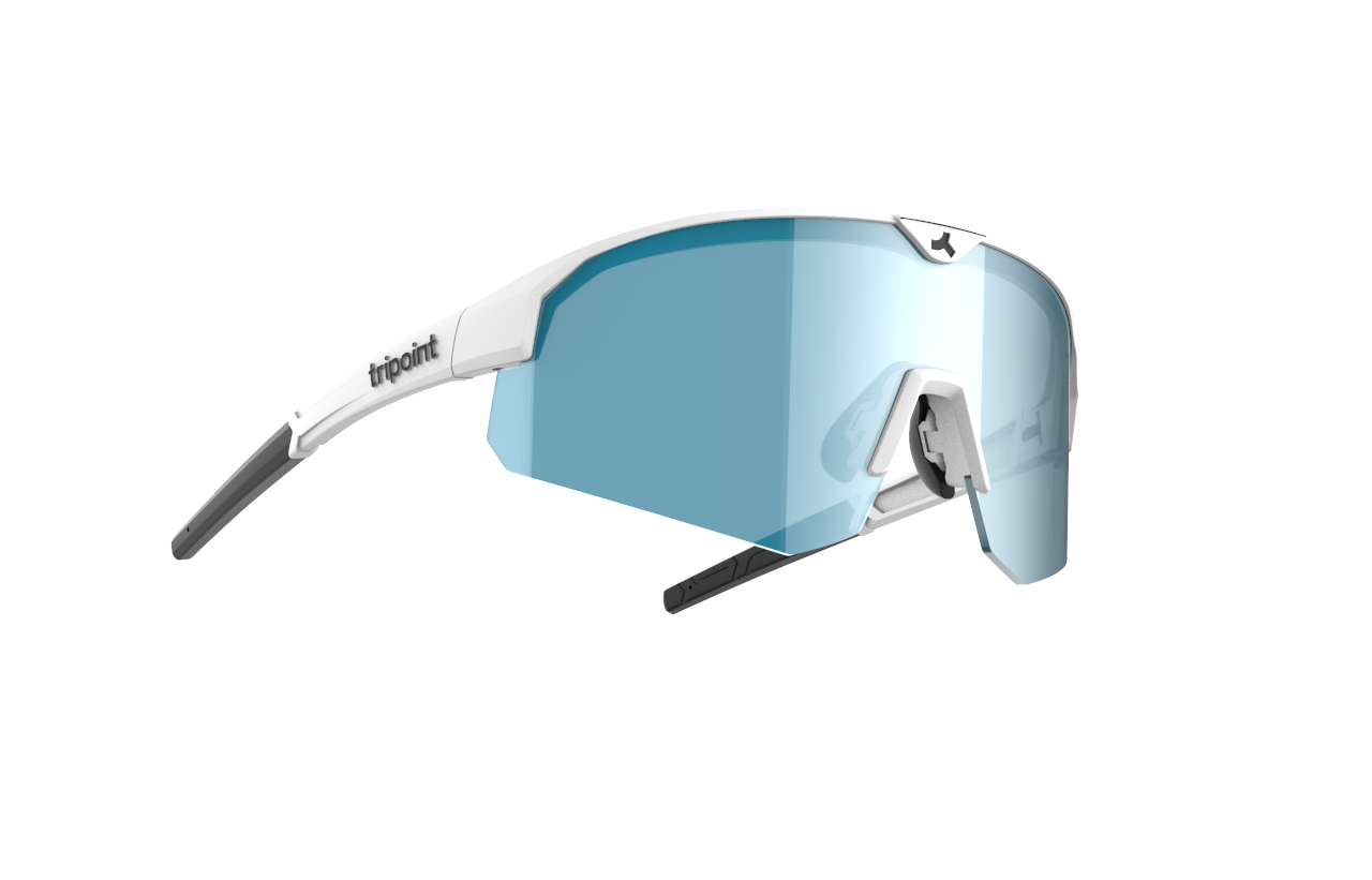 SÄHKÖPYÖRÄT.NETin Tripoint Mount Mist Small -urheiluaurinkolaseissa on valkoiset kehykset, sinisävyiset ympäryslinssit, mustat nenätyynyt ja ohuet mustat ohimokärjet. Tripoint-logo näkyy vasemmassa varressa tavallista vaaleanharmaata taustaa vasten.