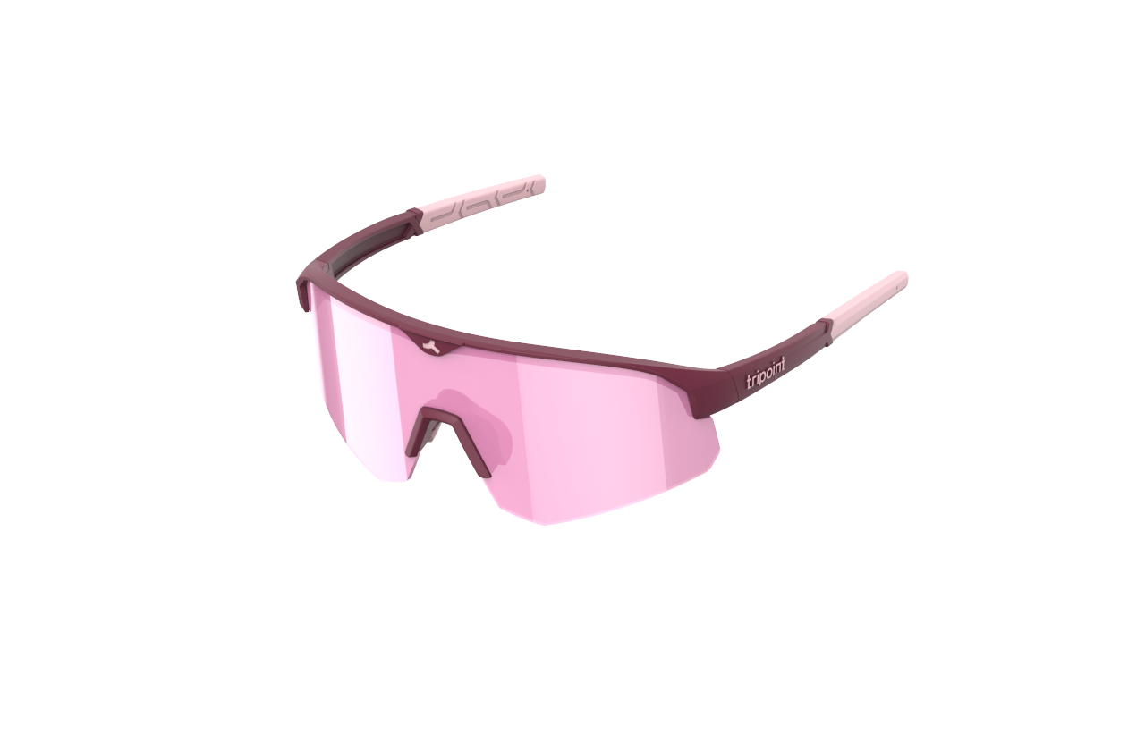 SÄHKÖPYÖRÄT.NETin Tripoint Mount Mist Pienissä urheilullisissa urheilulaseissa on ruskeankeltainen kehys ja vaaleanpunaiset sävytetyt ympäryslinssit, joissa on UV400-suoja. Tyylikkäässä muotoilussa on kaksiväriset ohimot ja tuotemerkki valkoisella pohjalla.