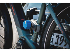 Lähikuva sähköpyörän rungosta, jossa on sininen lukko takapyörässä. Pyörässä on Yamaha-moottori ja vieressä on Thule XLC Azura Xtra VC-10 pyöränkuljetusteline, taitettava ja lukittava. Osa rekisterikilvestä ja renkaasta näkyy.