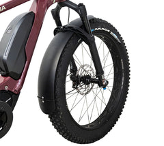 Lähikuva Helkama-sähköpyörän etupyörästä, jossa on paksu rengas, jousitettu haarukka ja HELKAMA: FATBIKE LOKASUOJASETTI ETEEN JA TAAKSE musta suojalevy. Myös pyörän runko ja akku ovat osittain näkyvissä.