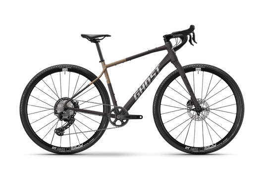 Ghost Asket Advanced on moderni gravel-pyörä, jossa on drop bars, hiilikuituhaarukka, levyjarrut, musta ja ruskea runko, isot nupukkarenkaat, ja Shimano GRX 1x12-vaihteisto. Kuvassa sivukuva valkoisella; Ghost-logo rungossa.