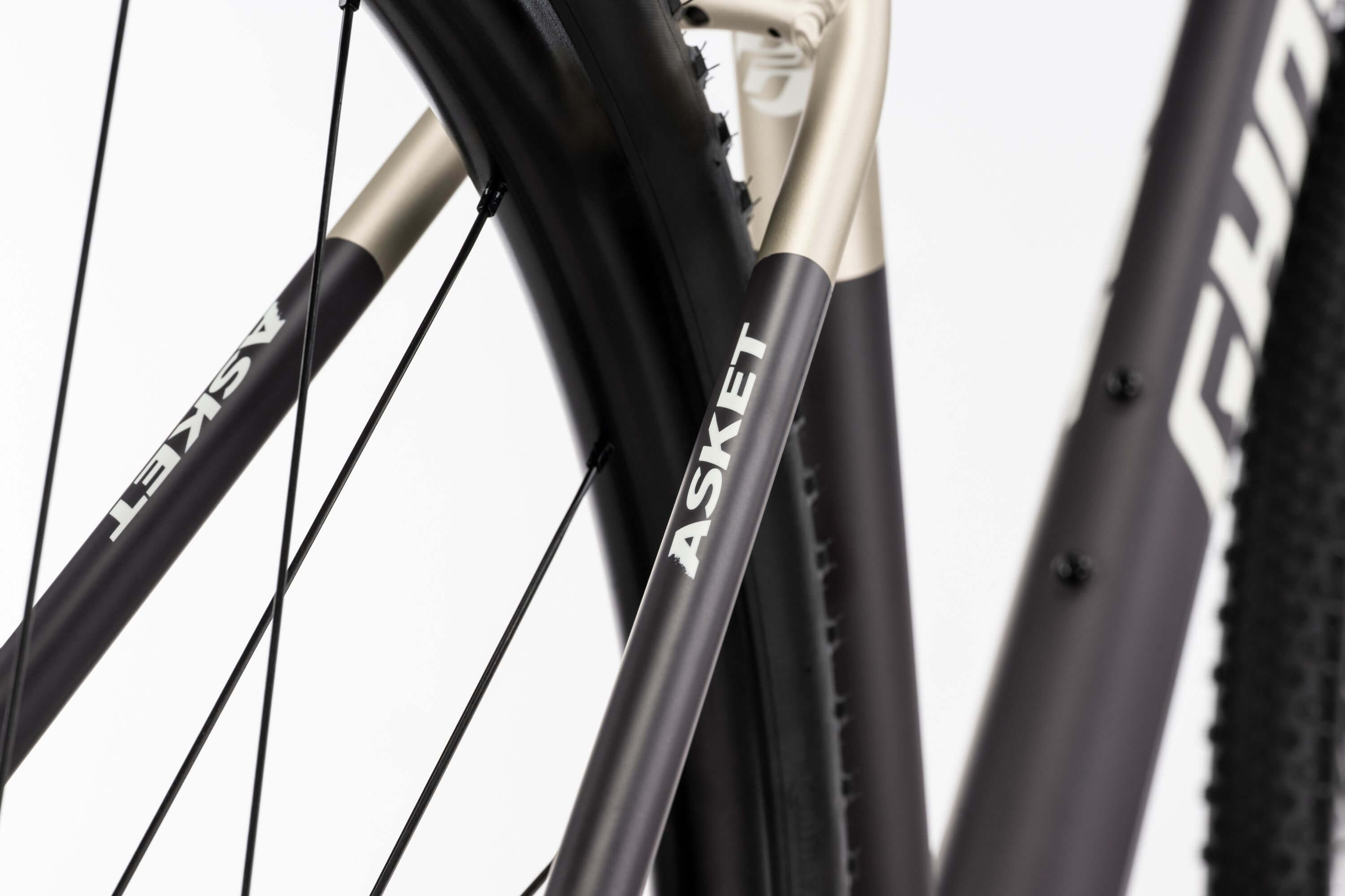 Ghost Asket Advanced -rungon ja -pyörän lähikuvassa näkyy GHOST-brändi mattamustassa putkessa, jossa on Shimano GRX -osat, vaaleaa taustaa vasten.