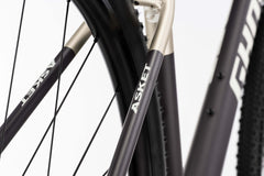 Ghost Asket Advanced -rungon ja -pyörän lähikuvassa näkyy GHOST-brändi mattamustassa putkessa, jossa on Shimano GRX -osat, vaaleaa taustaa vasten.