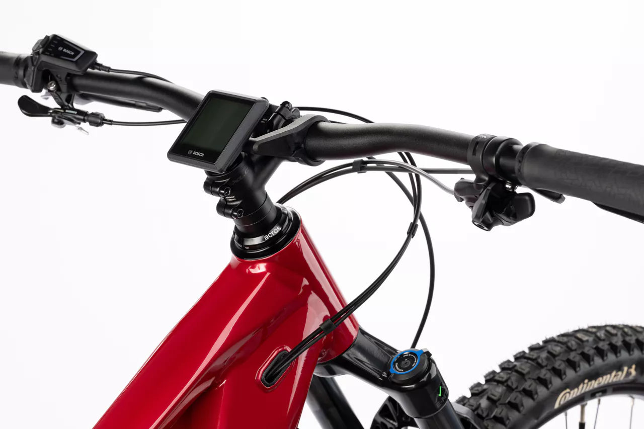 Lähikuva SÄHKÖPYÖRÄT.NETin punaisen Ghost E-ASX Essential 2026 -mallin ohjaustangosta ja näytöstä, jossa näkyy ohjauskaapeleita, rengas ja osia rungosta valkoista taustaa vasten.