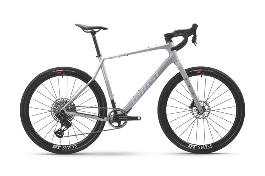 Ghost Asket CF LTD gravelpyörä by Ghost, näytetään sivulta valkoisella taustalla, on vaaleanharmaa hiilikuiturunko, pudota ohjaustanko, levyjarrut, ja paksut DT Swiss pyörät.