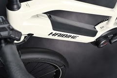 Lähikuva valkoisesta Haibike TREKKING 3 High S-koko by SÄHKÖPYÖRÄT.NET -mallista, jossa näkyy runko, Bosch Performance -akku, osittainen ohjaustanko ja takapyörä tummaa taustaa vasten.