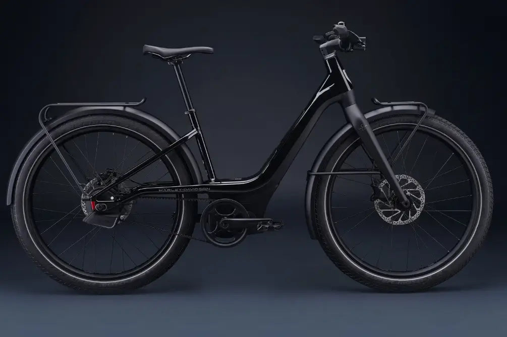 Serial1 Harley-Davidson: Serial 1 Rush Step-thru sähköpyörä, jossa on step-through-runko, levyjarrut, etu- ja takalokasuojat sekä takateline, on kuvattu sivulta tummaa taustaa vasten.