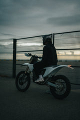 Valkoinen sähkömoottoripyörä teollisuusalueella otettu kuva