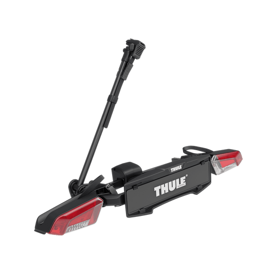 Thule VeloLite pyöränkuljetusteline on Thulen musta pyöräteline, jossa on punaiset heijastimet, rekisterikilven pidike ja pystyvarsi vetokoukkuun kiinnitettävässä käytössä, kuvassa valkoista taustaa vasten.