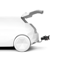 Valkoisessa geometrisessa autossa, jossa on avoin takakontti, näkyy Thule VeloLite pyöränkuljetusteline, jonka Thule on kiinnittänyt takaosaan mustan latauslaitteen viereen, korostaen sen sähköauto-ominaisuutta tavallista valkoista taustaa vasten.